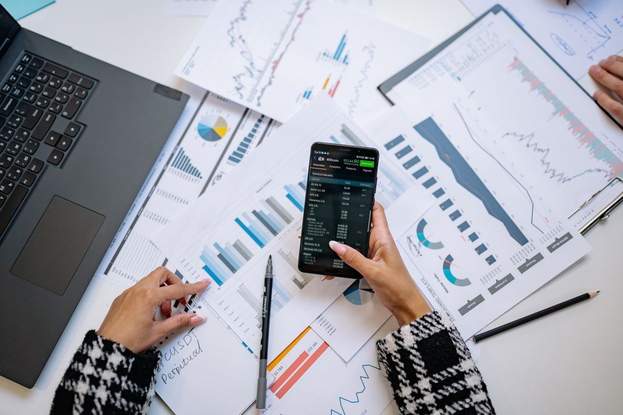 Une vue plongeante sur des graphiques et un smartphone dans un bureau, illustrant l’analyse de données.